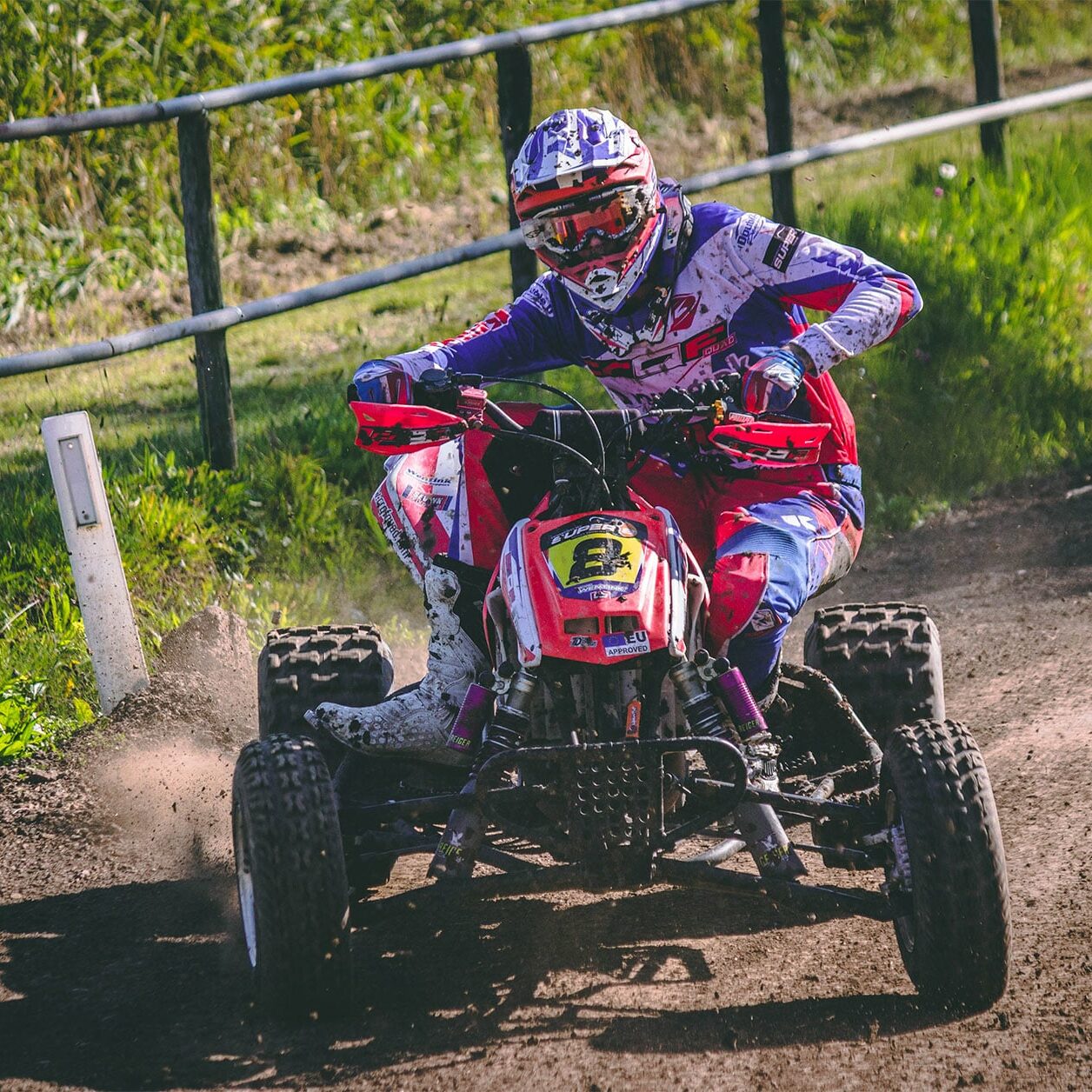 quad bike rider racing on a dirt track on a sunny day